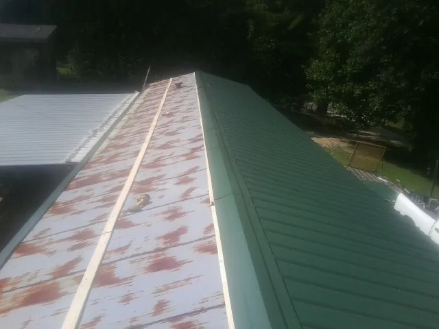 Old rusted panels beside newly installed green metal roofing — Wind Damage Roof Repair by Roofing Brothers in Rockaway Beach