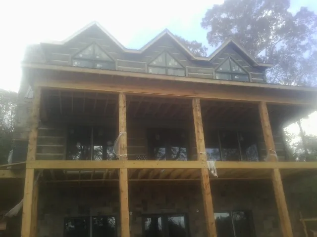 Dormers and porch framing on a large log home under construction — Roof Coating work by our crew in Rockaway Beach