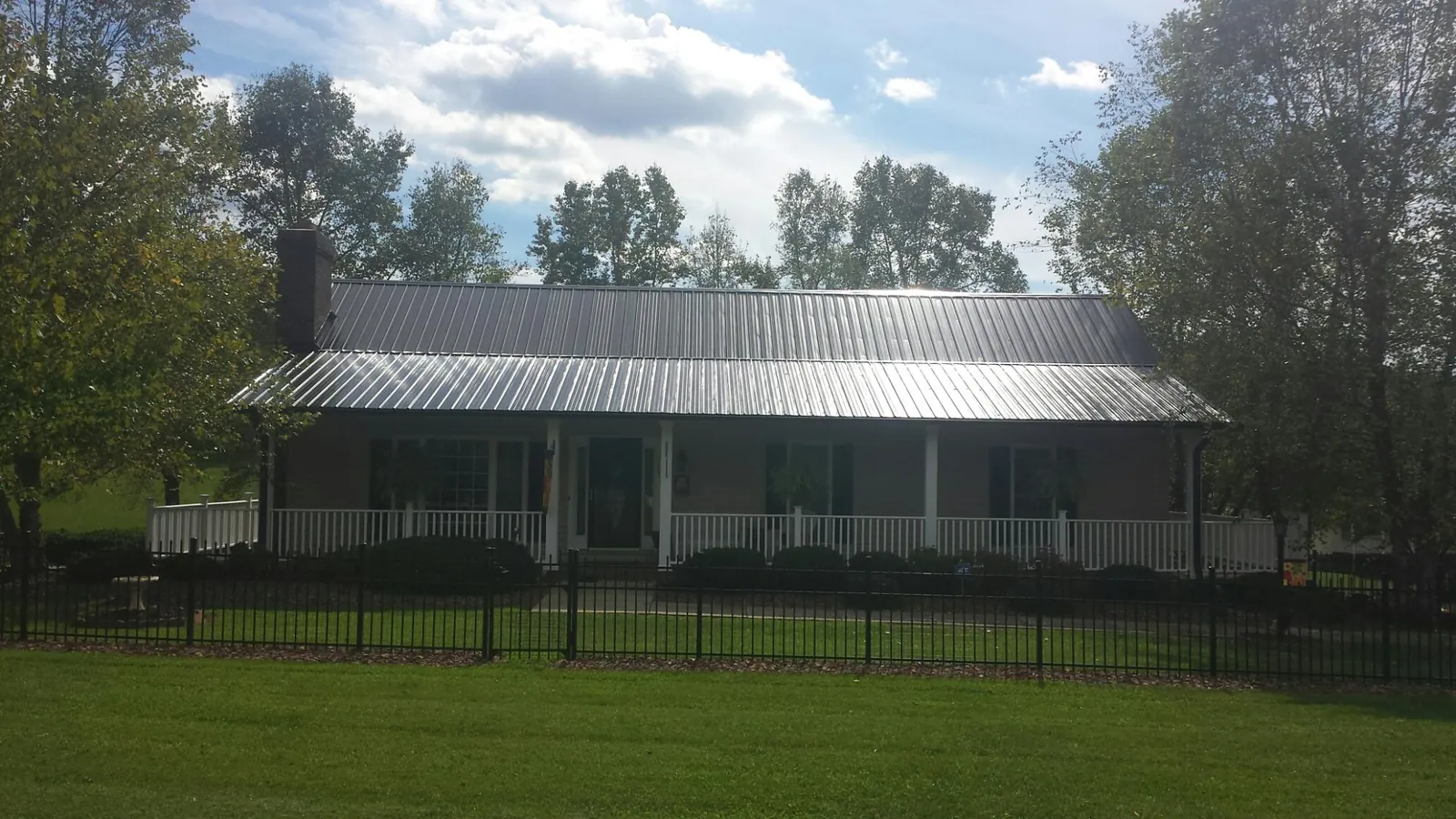 Gray metal roof on a brick ranch with a full width front porch — Gutter Guard Installation work by our crew in Rockaway Beach